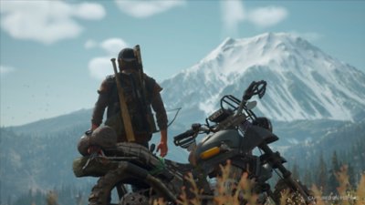 Days Gone Remastered screenshot showing the protagonist looking out on a mountain vista while leaning against his motorbike