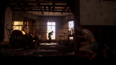 The Texas Chain Saw Massacre - Screenshot che mostra l'interno in penombra di una casa con un personaggio che si nasconde dietro a un muro da qualcuno che impugna un'arma.