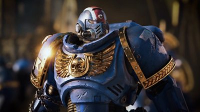 Warhammer 40,000: Space Marine 2 - Screenshot di un marine in armatura blu in primo piano con uno stemma dorato sul petto